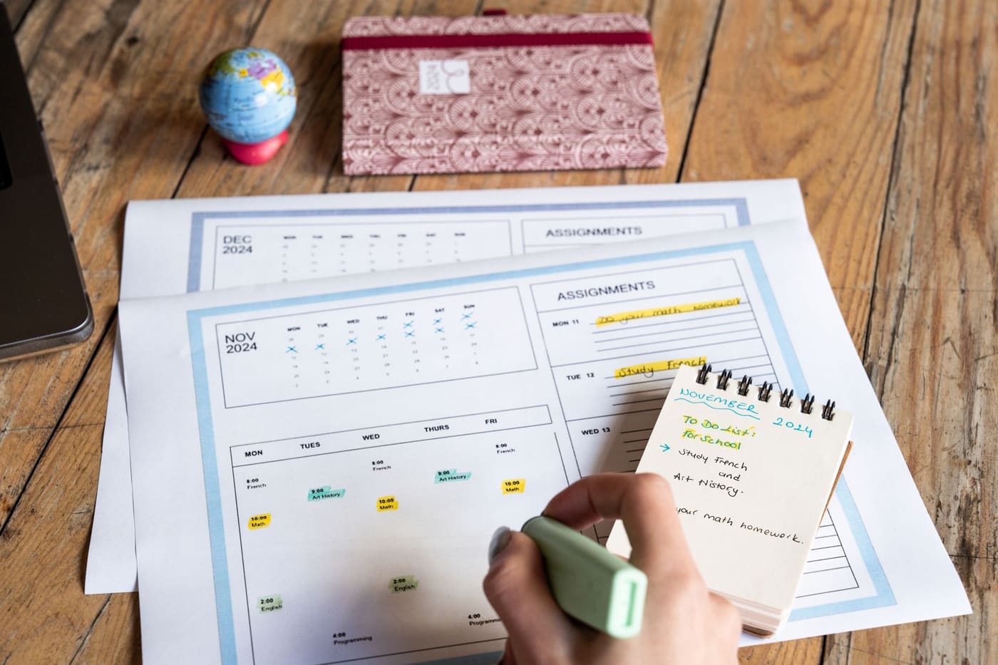 A person marking a calendar and notepad on a wooden table